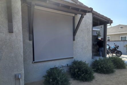 Exterior view of a Danville home featuring newly installed motorized window shades, providing sleek sun protection above garden shrubs.