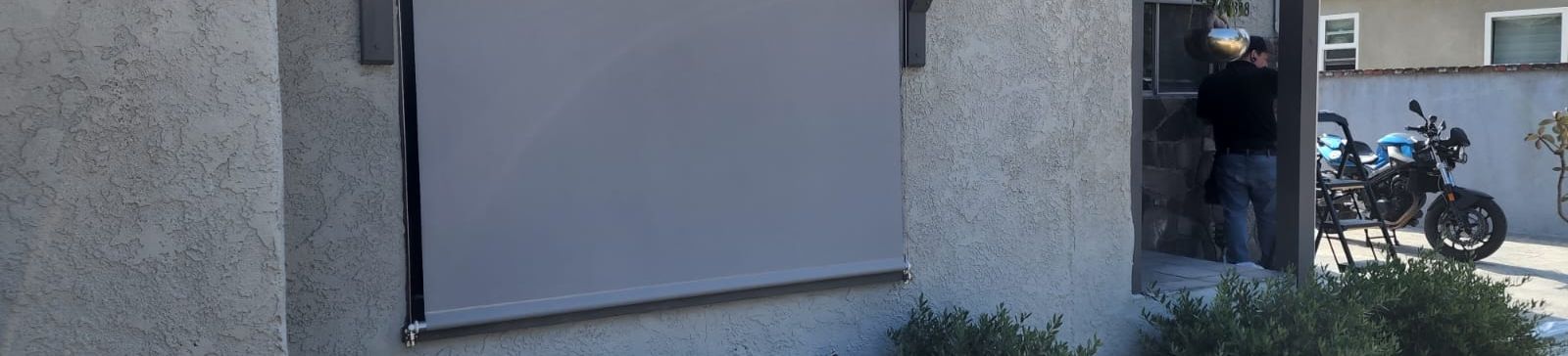 Exterior view of a Danville home featuring newly installed motorized window shades, providing sleek sun protection above garden shrubs.